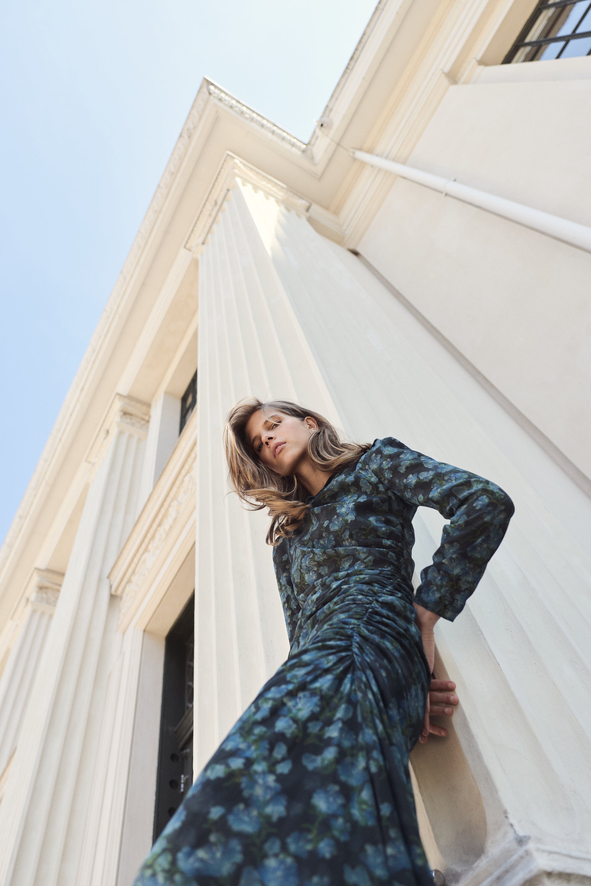 Woman in a blue floral dress standing in front of classical architecture